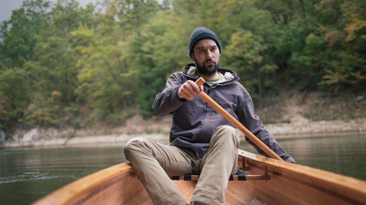Man paddling canoe in the lake forest.