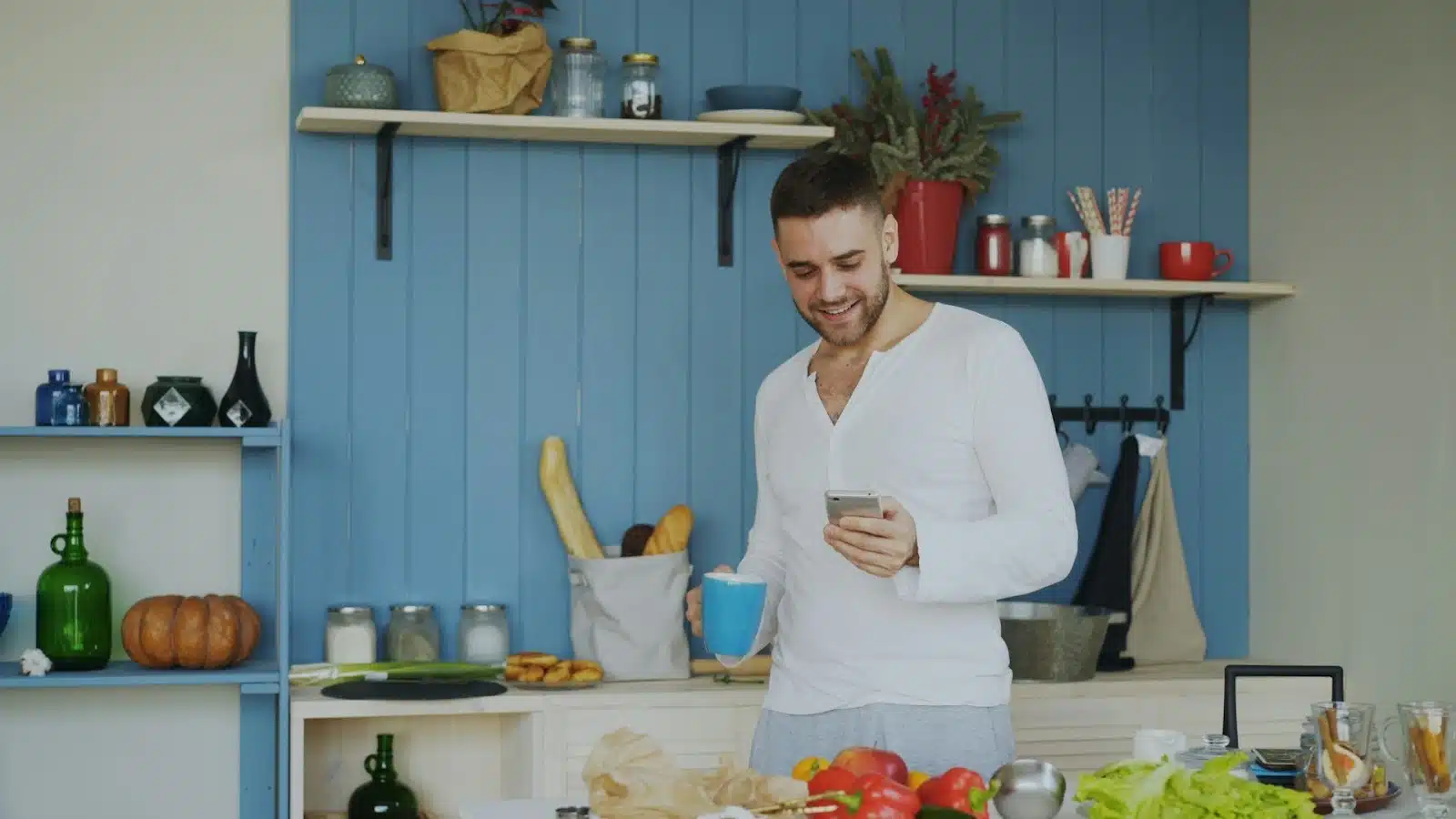 A man checking his phone while holding a mug