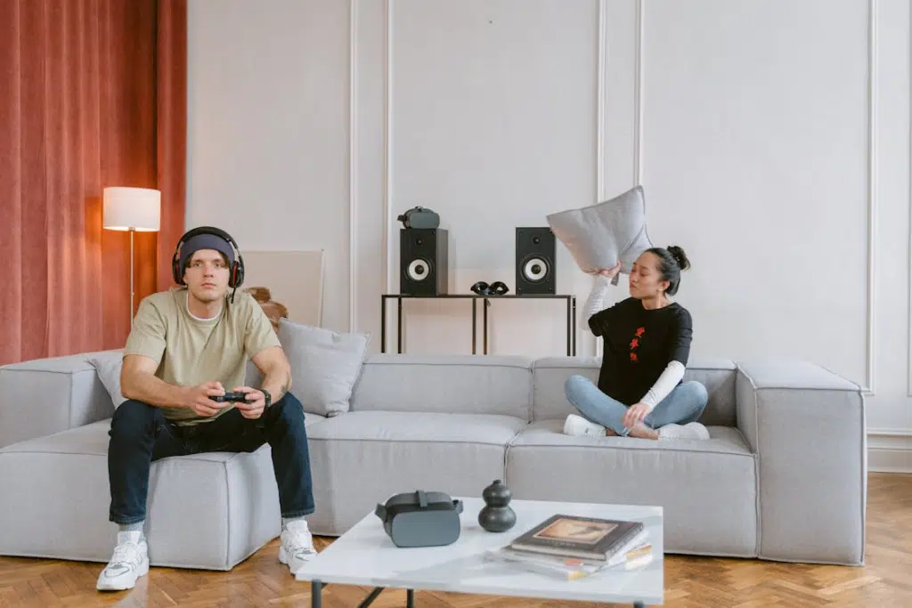 Man Sitting on Sofa While Playing beside angry woman