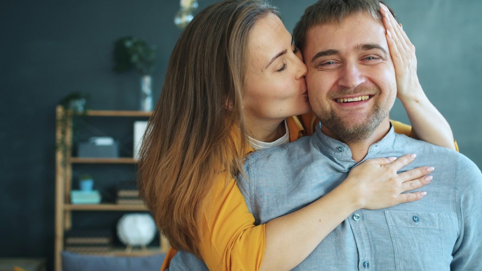 A woman kissing a man on his cheeks