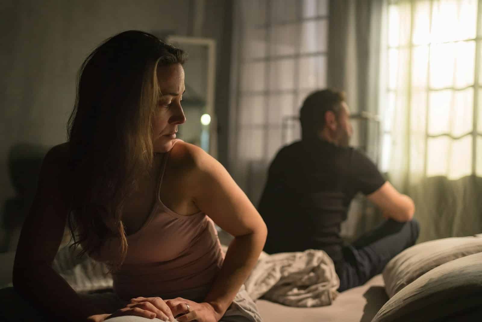 A couple sitting apart in their bed