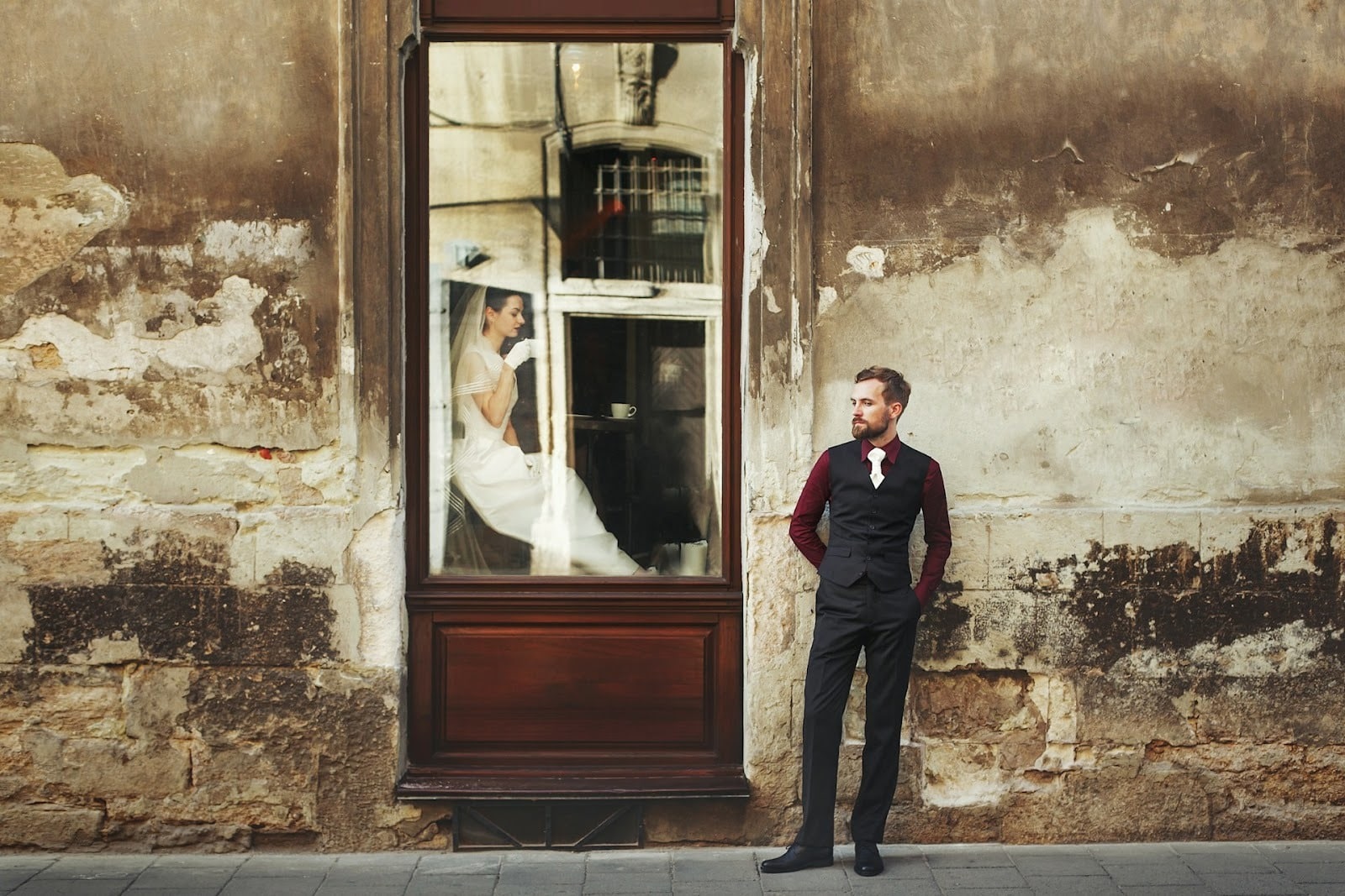 A man standing outdoors and a woman in a window
