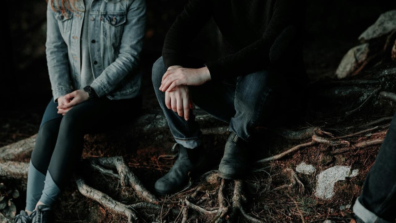 A group of people sitting quietly on rocks in a forested area.
