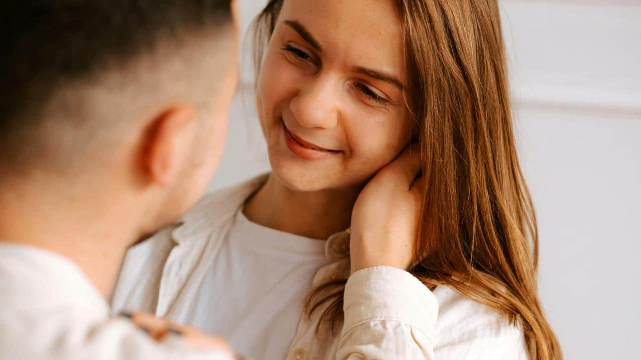 A woman smiling at someone in a close-up indoor scene.
