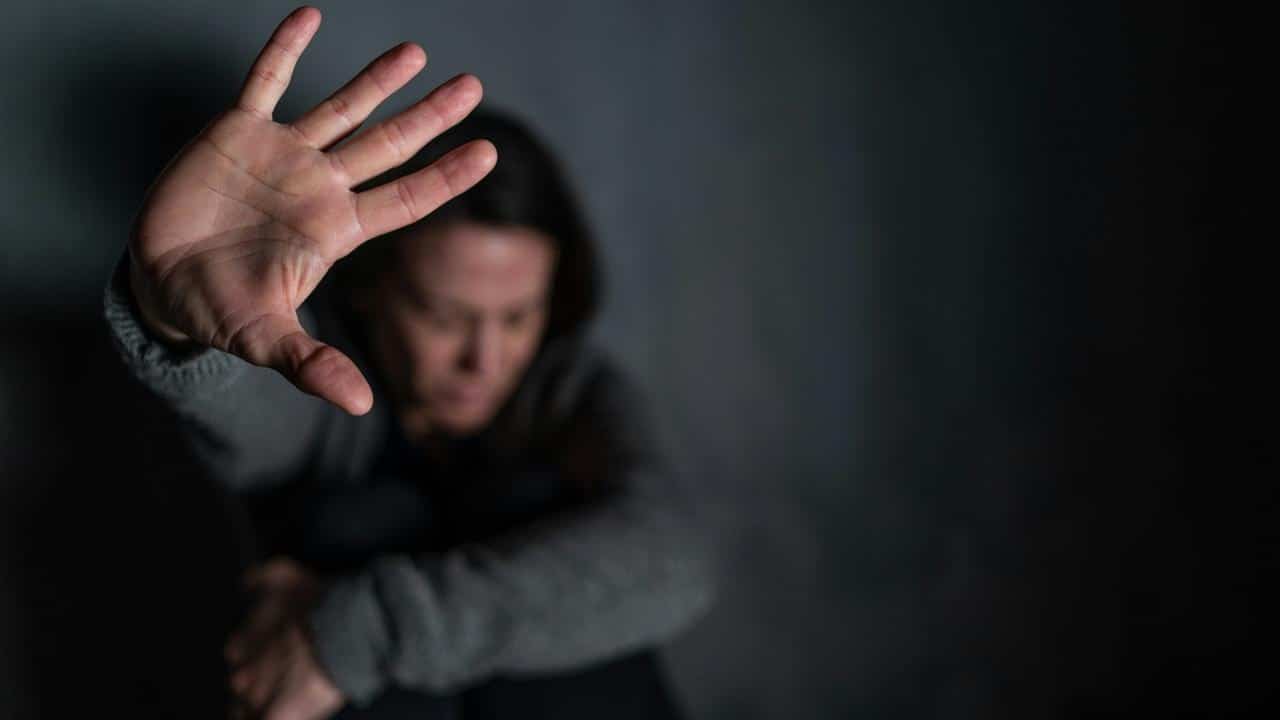 A person holds up a hand as if blocking or refusing something.