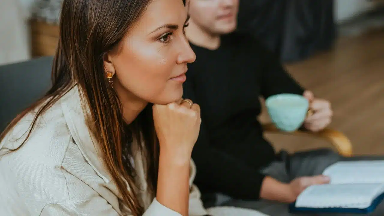 A woman rests her chin on her hand while listening.