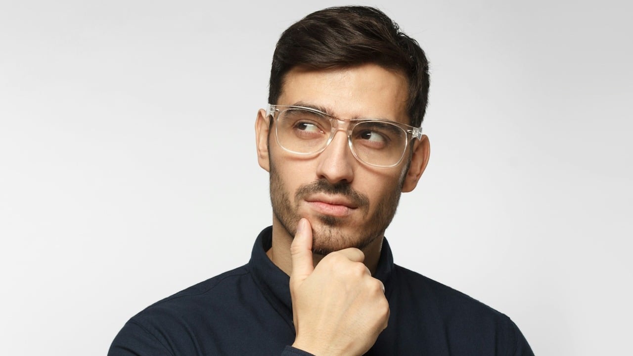 A lightly bearded man wearing glasses looking contemplative.