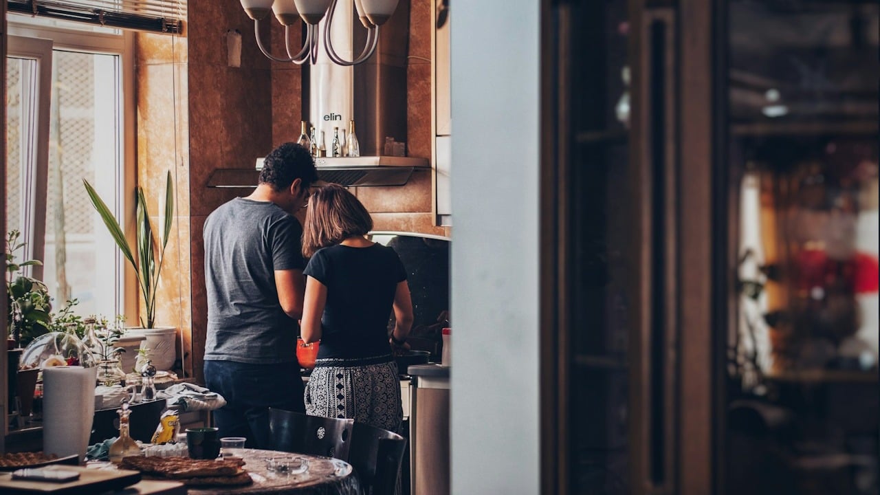A man and woman standing in front of a cooking range.