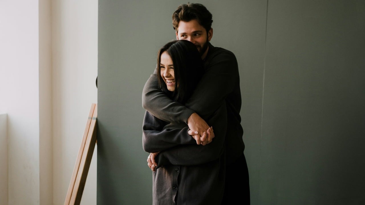 A man hugging his girlfriend from behind.