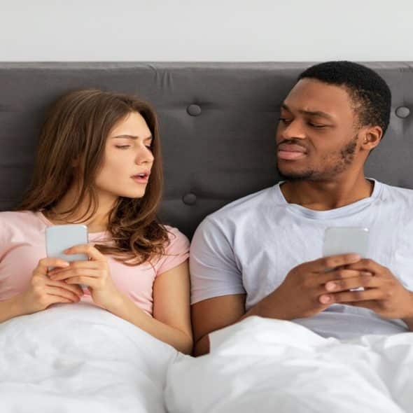 A couple looking at each other’s phones