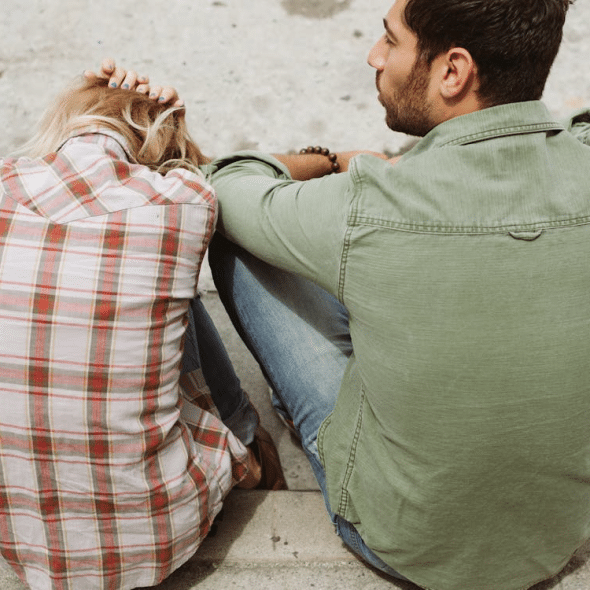 Unhappy couple sitting and woman cowering in fear