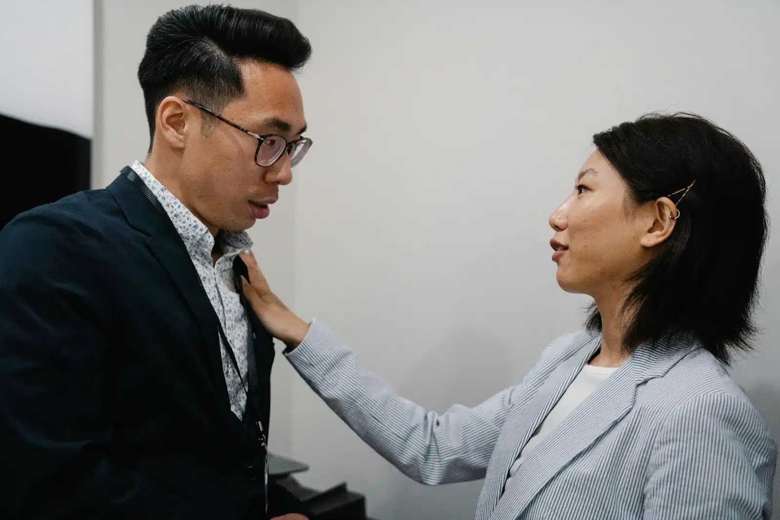 A woman fixing man’s suit