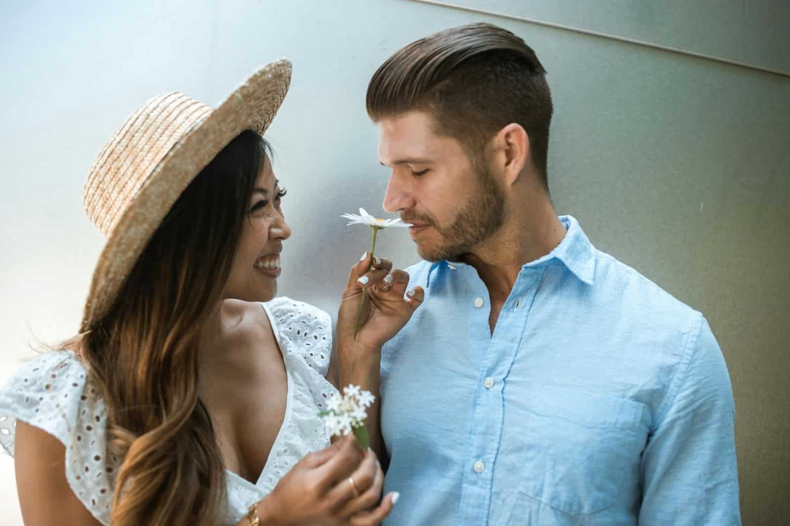 A woman holding a flower and a man smelling it