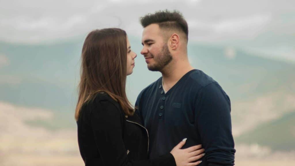 A couple standing close looking in the eyes of each other.