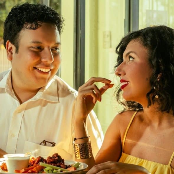 A smiling couple is having meal and looking at each other.