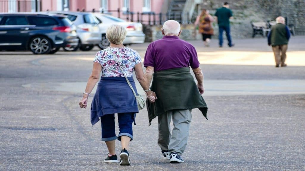 An older couple holding hands while walking