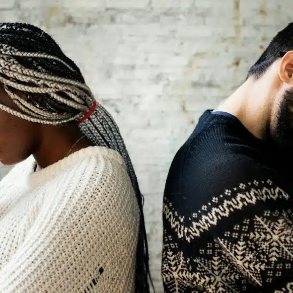 A couple touching their heads and appearing to be stressed, standing back-to-back after a fight.