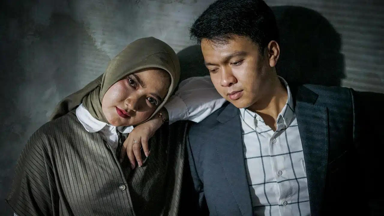 A woman putting her arm on a man’s shoulder while they are standing close to each other.