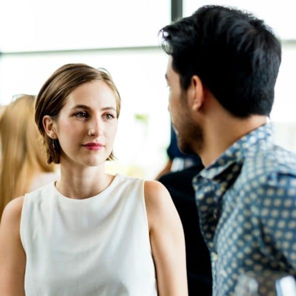A woman looking at a man while they sit at a table in a restaurant.