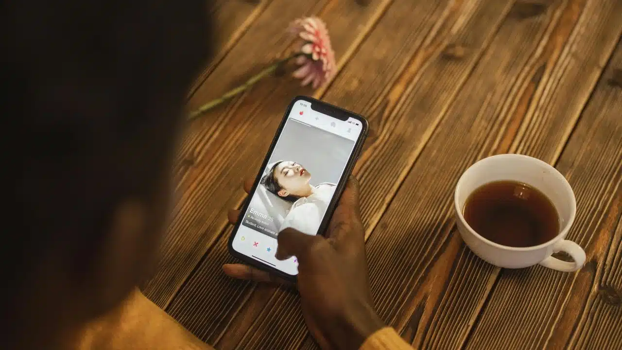 High angle view of a person holding a smartphone displaying a dating app profile.