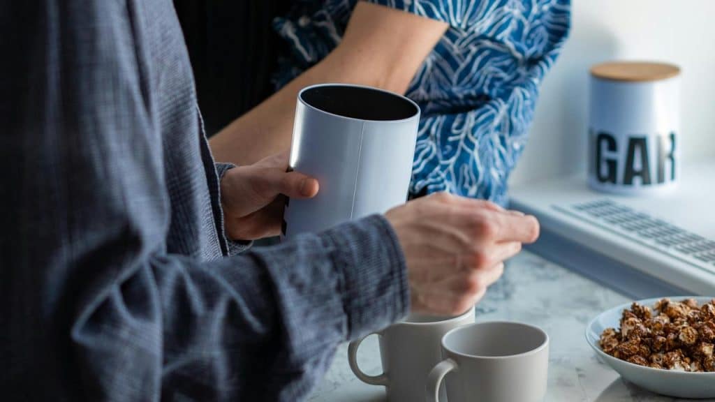 A person pouring coffee into a mug in a kitchen.