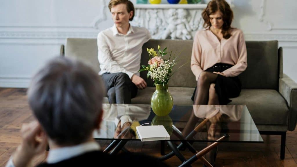 A couple sitting on a couch during a therapy session.