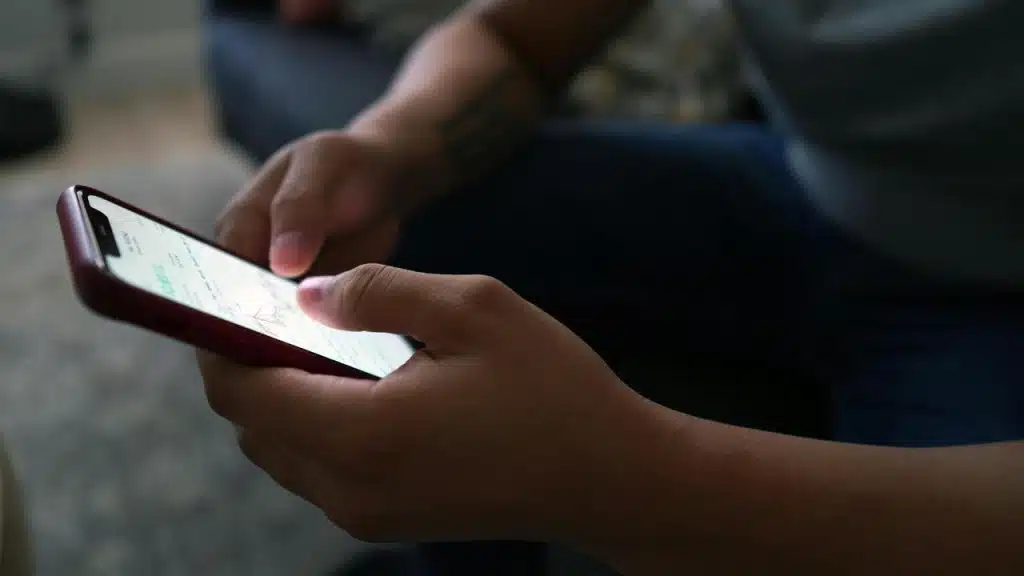 A close-up of hands using a smartphone indoors.
