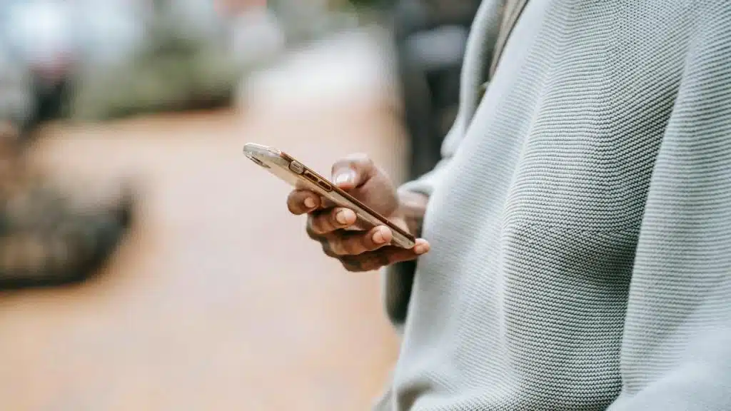 A close-up of a person holding a smartphone outdoors.