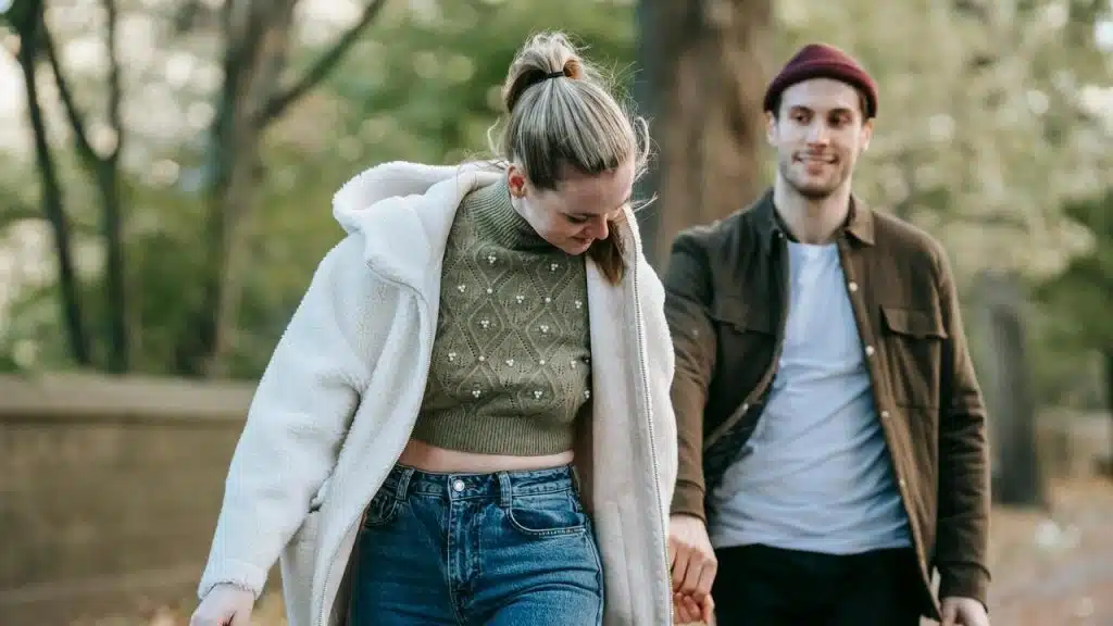 A couple walking outdoors in a park during autumn.