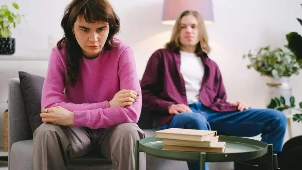 A couple sitting apart on a couch after an argument.