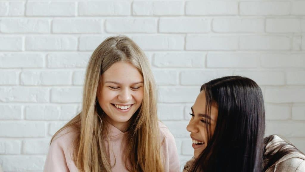 A pair of friends laughing together indoors.