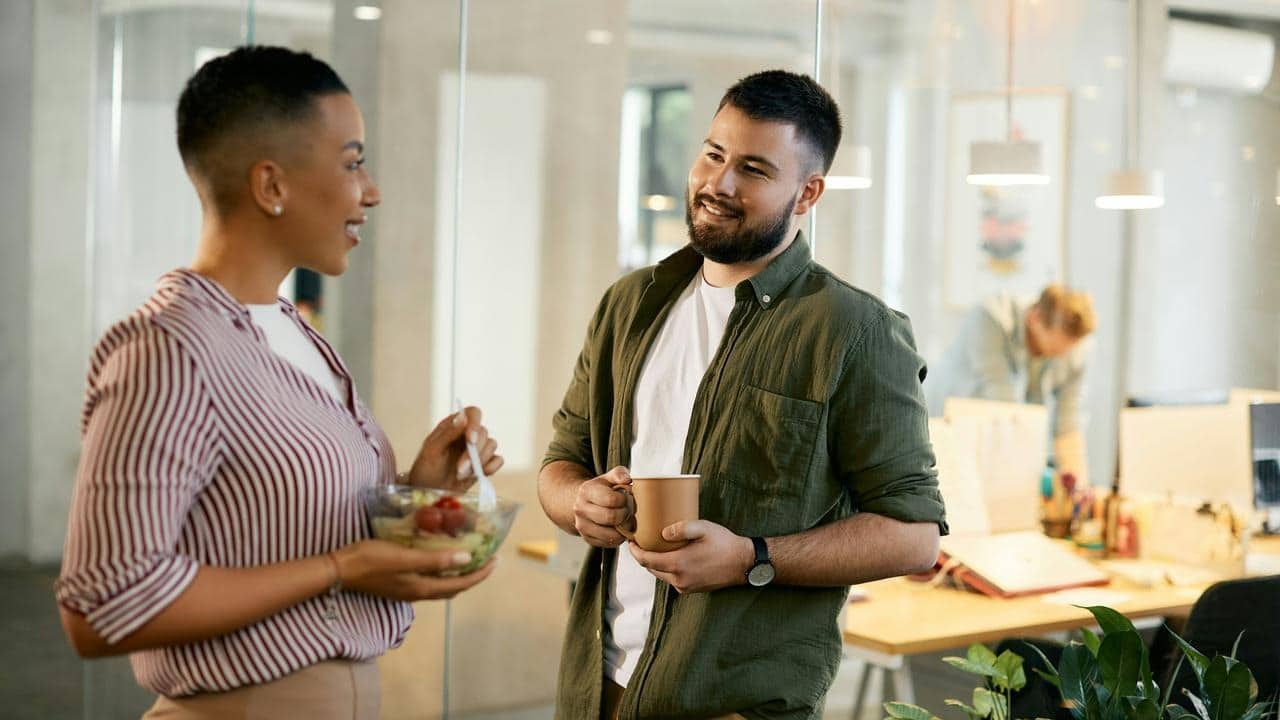A man and woman talking and smiling in an office setting.