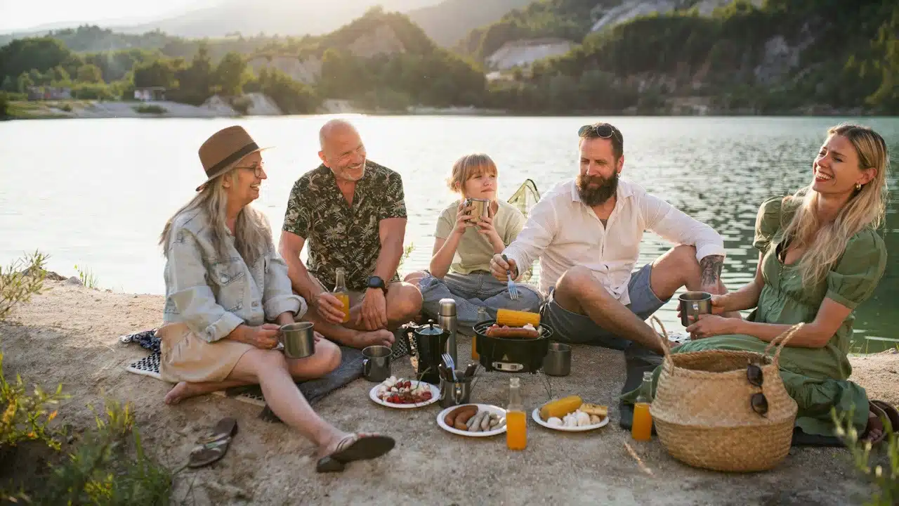 A happy multigenerational family on a summer holiday trip barbecue by the lake.