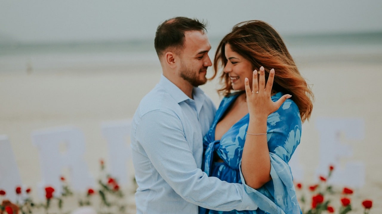 A couple embracing on a beach with rose decorations.