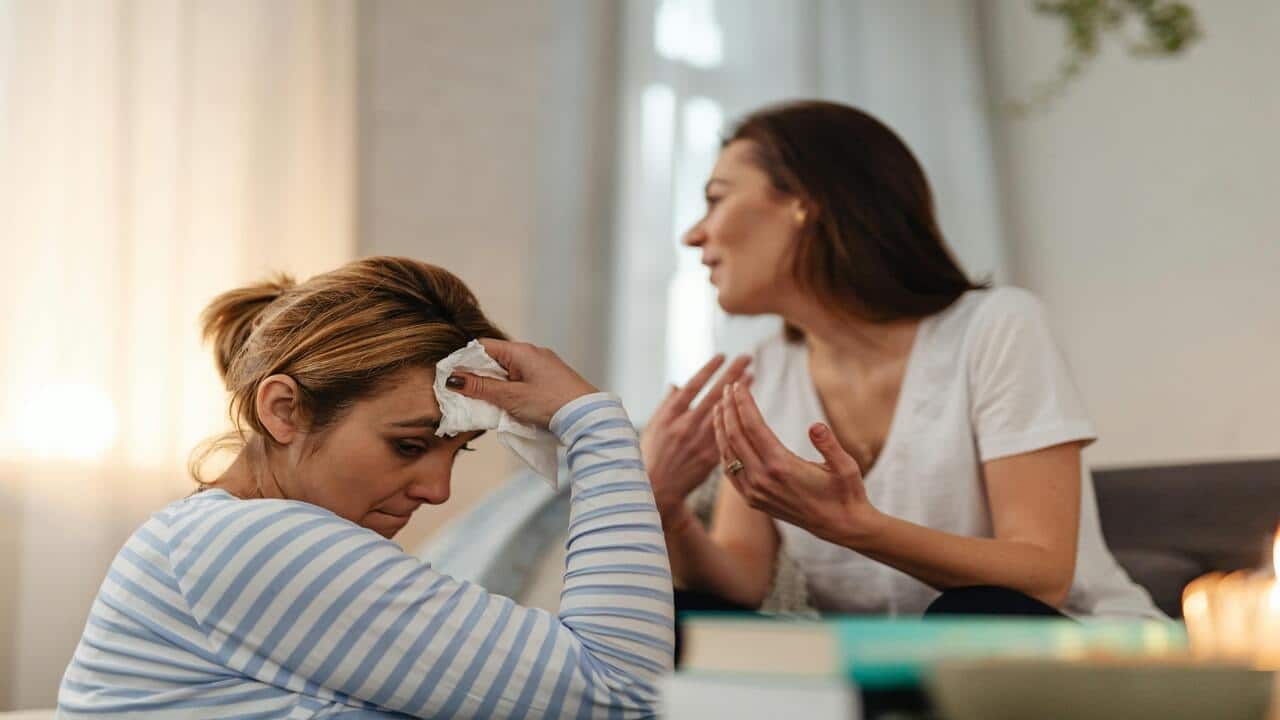 A woman looking sad while her friend talks