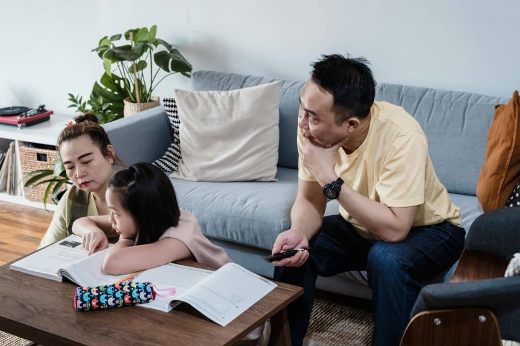A woman teaching a child and a man beside them