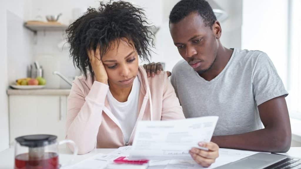 A man and woman sit together at a table while looking at a white document.