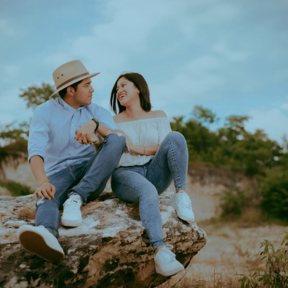Couple Sitting on Rock while Looking at Each Other