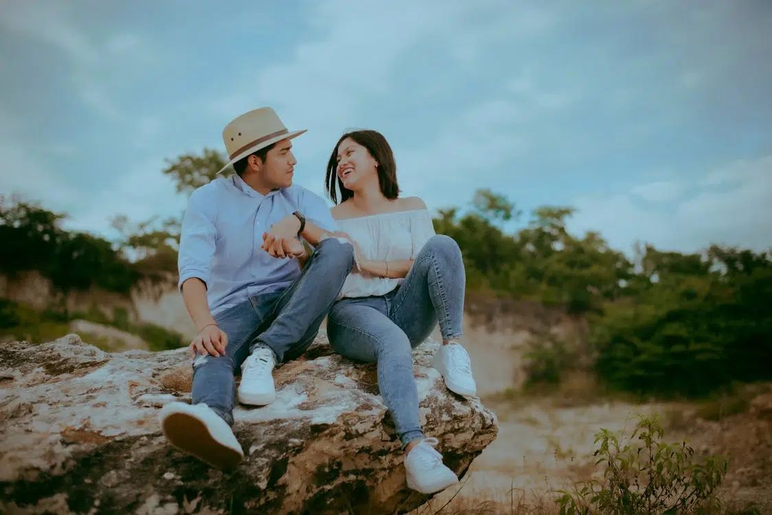 Couple Sitting on Rock while Looking at Each Other