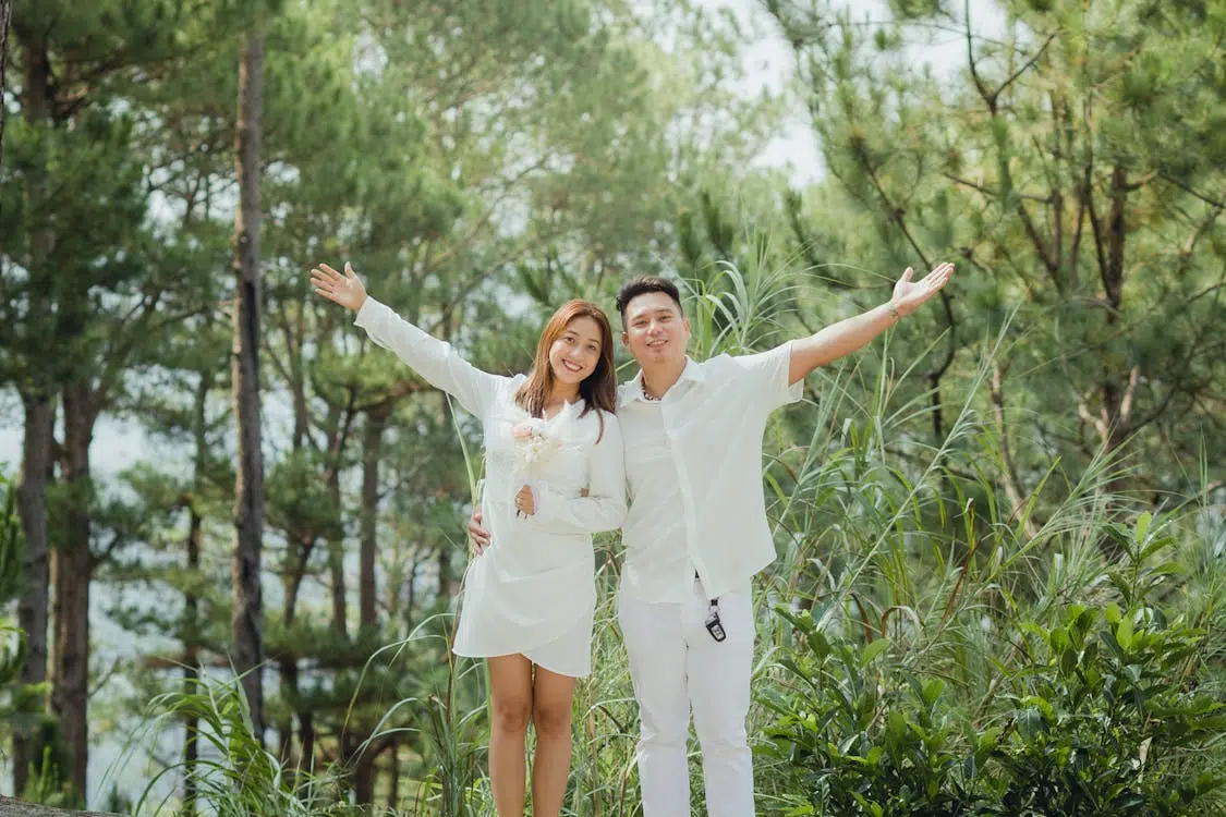 Couple Standing in a Park with Spread Arms and Smiling