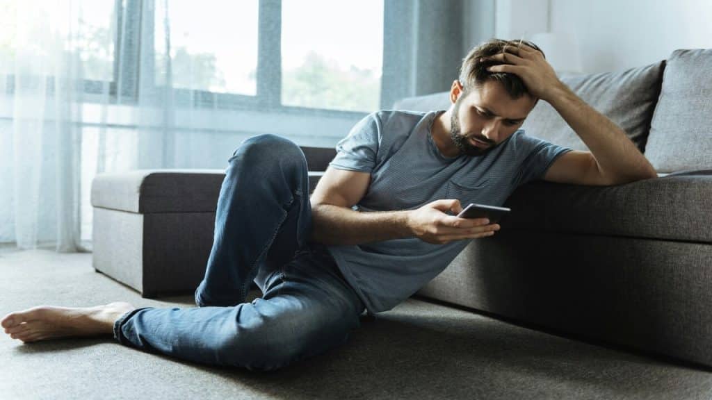 A man looking upset at what he’s seeing on his phone