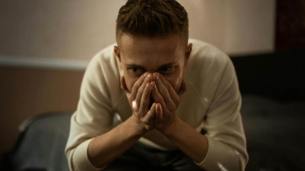 A person sitting with their hands covering their mouth in distress.