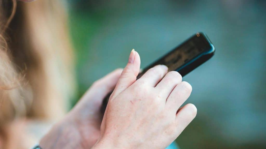 A person holding a smartphone and using their thumb to scroll.