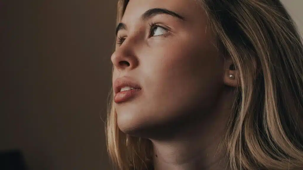 A close-up of a woman looking upward with a thoughtful expression.