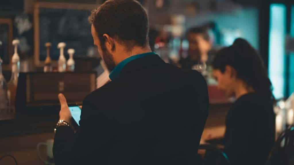 A man using a smartphone while standing at a café counter.