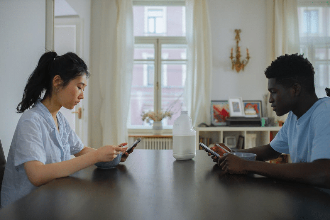Couple sitting apart on phones ignoring each other