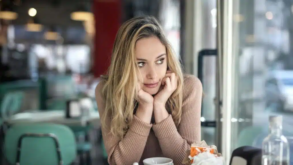 A person sitting in a café, gazing thoughtfully out the window.