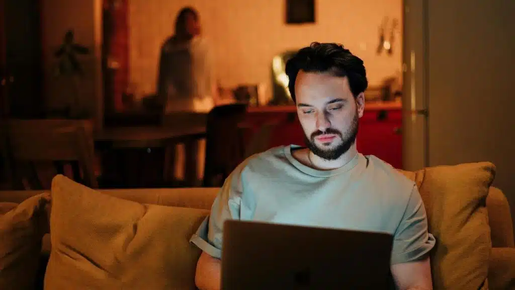 A person sitting on a couch using a laptop at night.