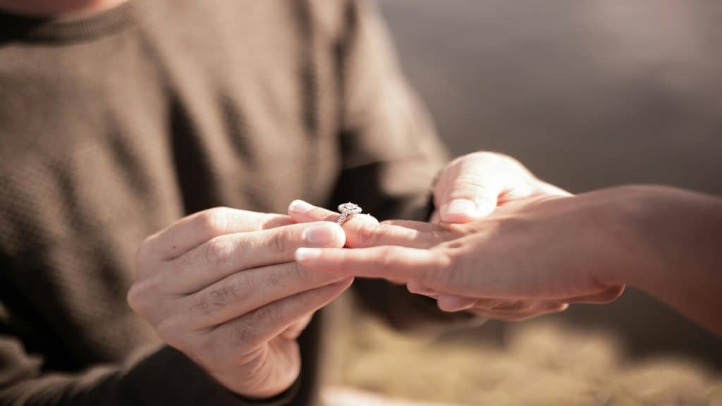 A man putting on an engagement ring on a woman