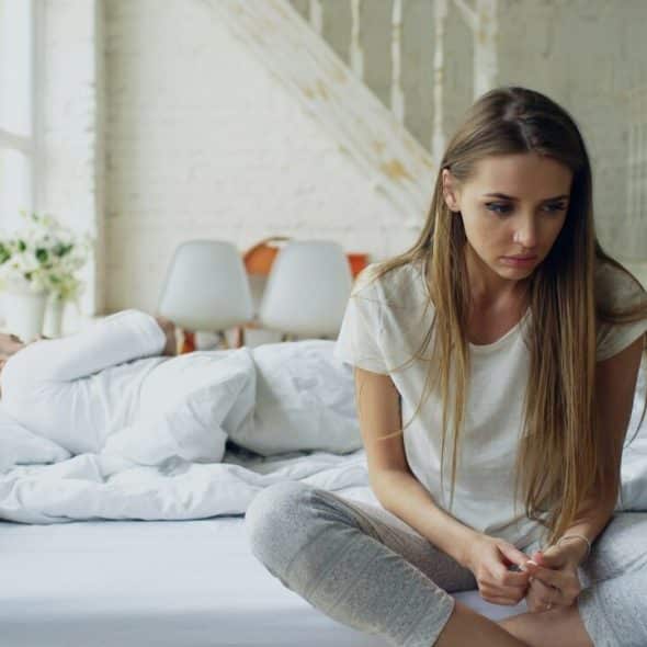 A woman looking sad while her husband sleeps
